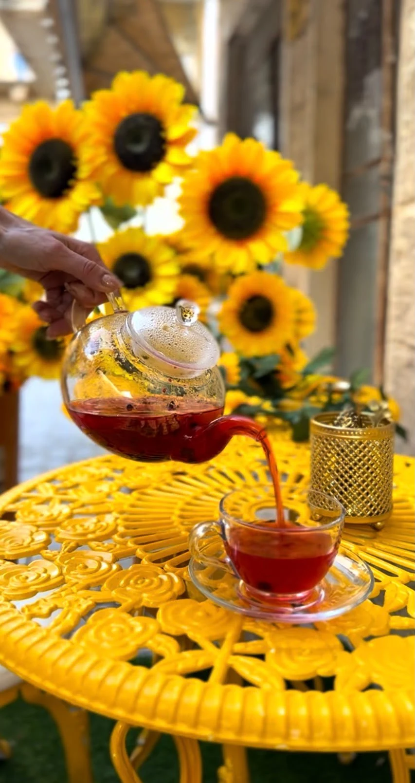 Fresh tea being poured beside bright sunflowers